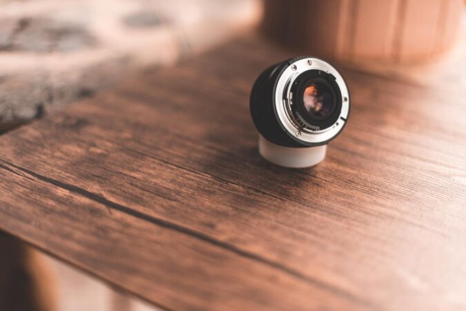 Objectif d'appareil photo ou de caméra miniature posé sur une surface en bois, mettant en avant la compacité des Accessoires Espion