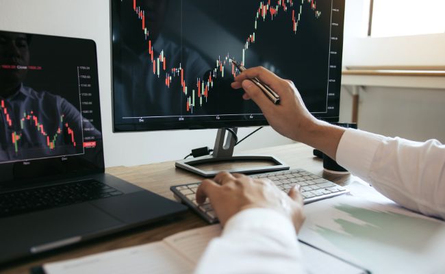 Main d'un analyste pointant un chandelier sur un écran pour la stratégie d'option trading.