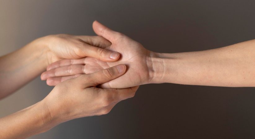 Un praticien effectue un massage réflexologique de la main pour calmer l'anxiété en pressant la paume ouverte.